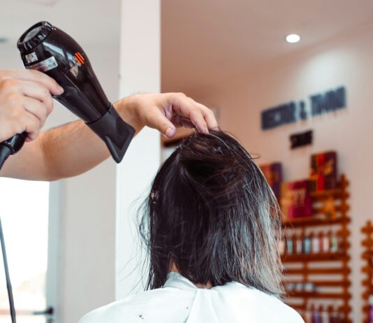 “건강한 헤어케어, 일상에서 시작하세요…지속가능한 뷰티 트렌드로 자리잡아” woman in white shirt holding hair blower